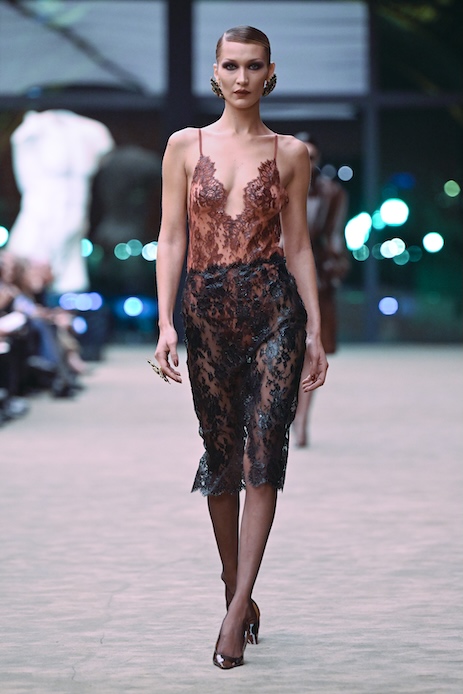 Bella Hadid alla Paris Fashion Week 2026 con chignon tirato e abito in pizzo rosso