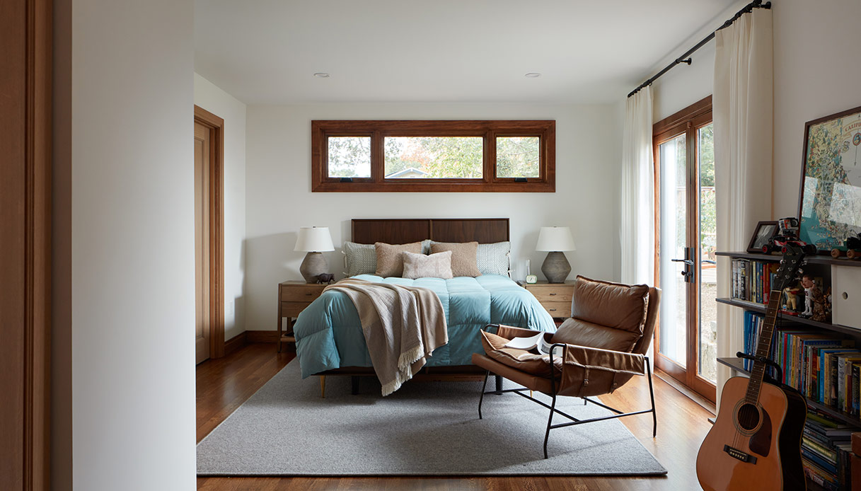 Camera da letto luminosa con letto imbottito e porte finestre