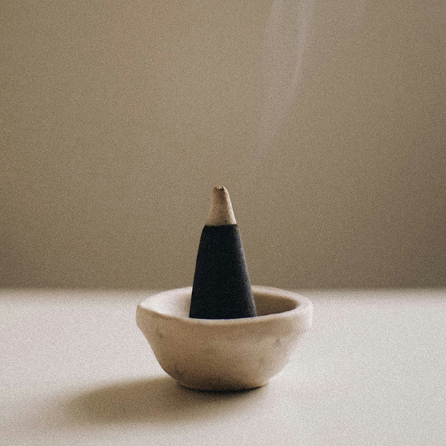 cono di incenso acceso su bruciatore in ceramica dal design minimal