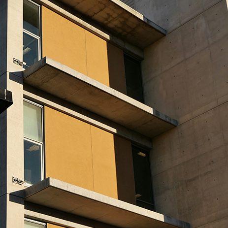 Edificio moderno con balconi e pannelli frangisole color ocra che schermano le finestre