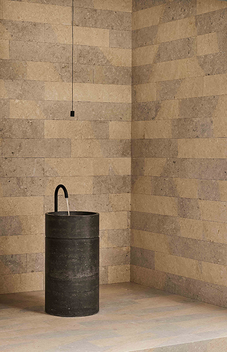 Bagno con pareti rivestite in pietra Perla Blu di Grassi Pietre e lavabo cilindrico in pietra scura