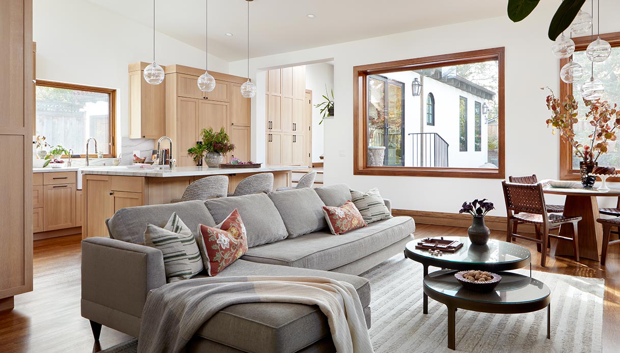 Open space con cucina in legno chiaro e soggiorno luminoso