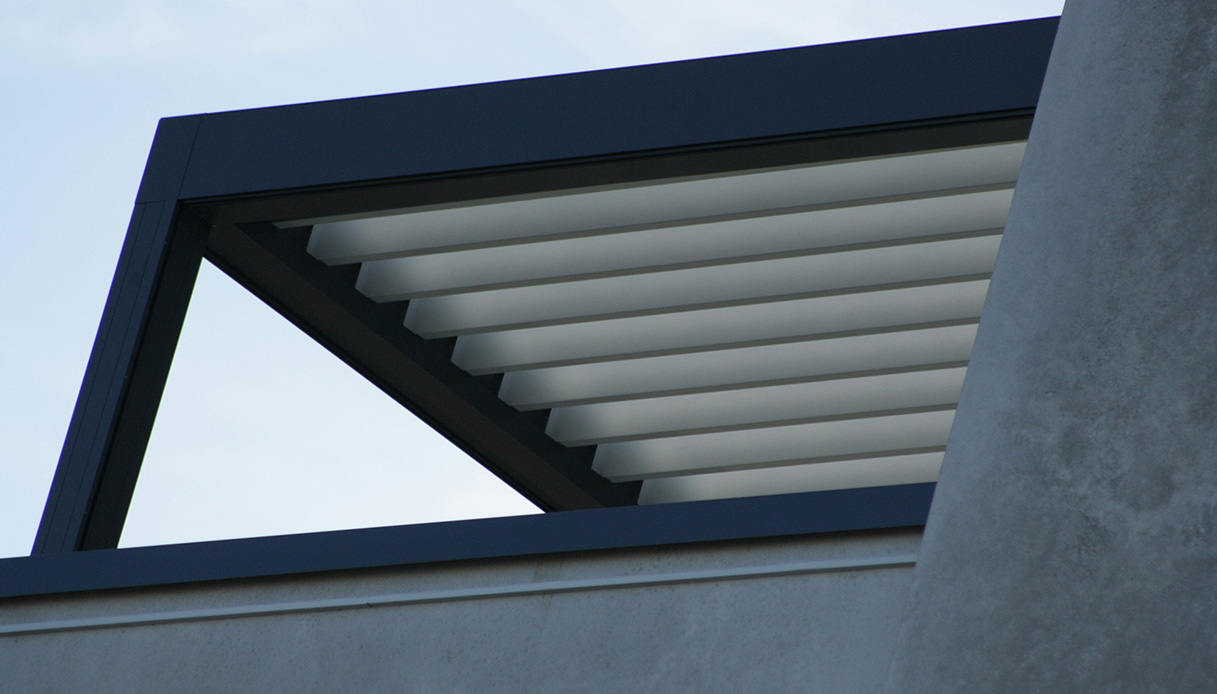 Pergola bioclimatica moderna con lamelle bianche orientabili vista dal basso contro il cielo