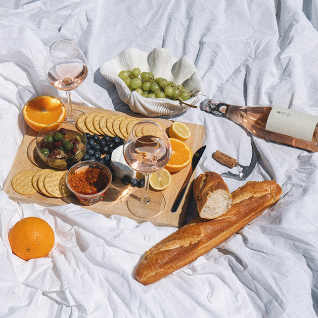 picnic con vino rosé frutta pane e tagliere su coperta bianca all’aperto