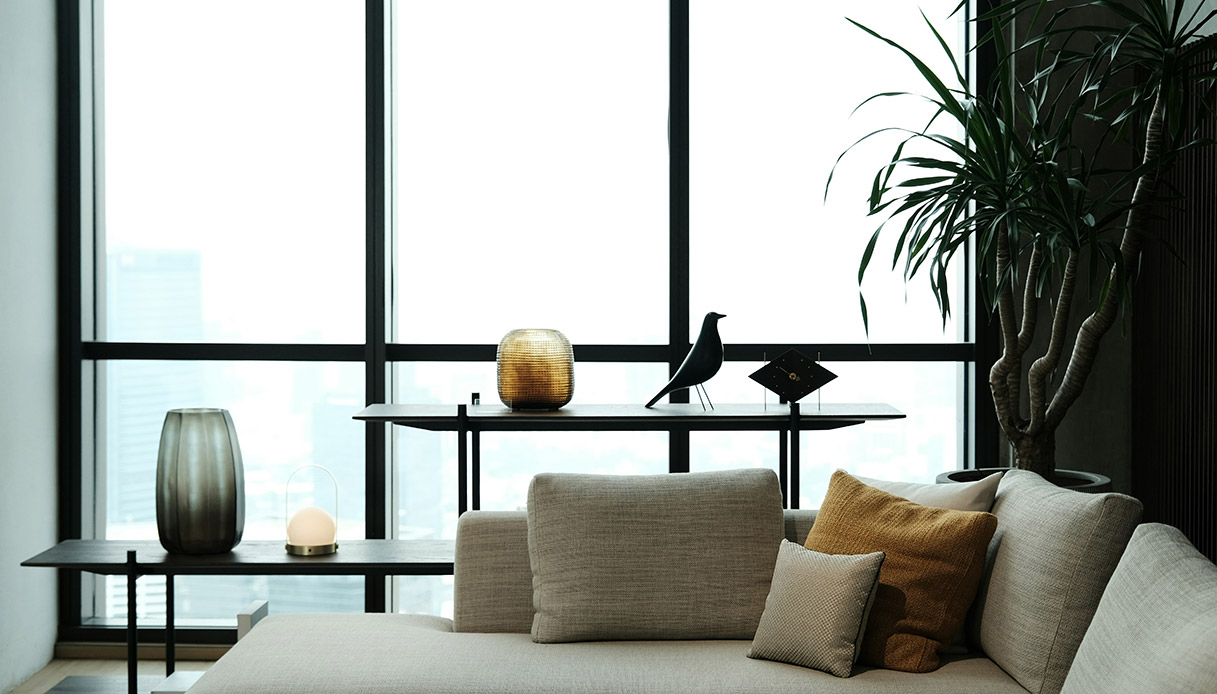 soggiorno moderno con divano chiaro davanti a grandi finestre e arredi minimal