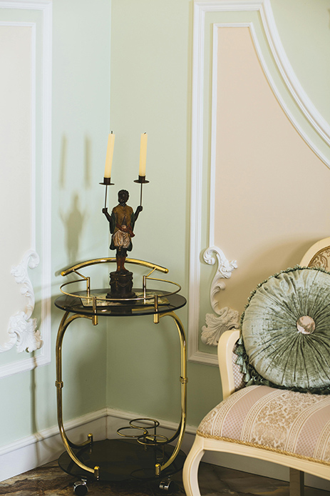 dettaglio parete con boiserie classica e tavolino dorato in stile parigino