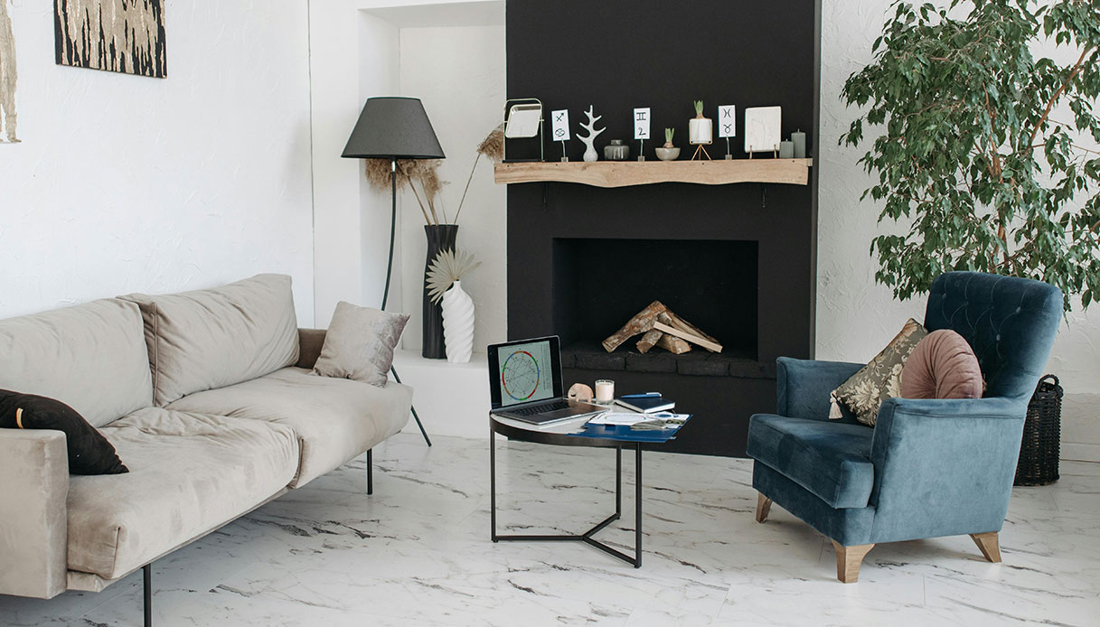 soggiorno minimal con camino nero, divano beige e poltrona blu