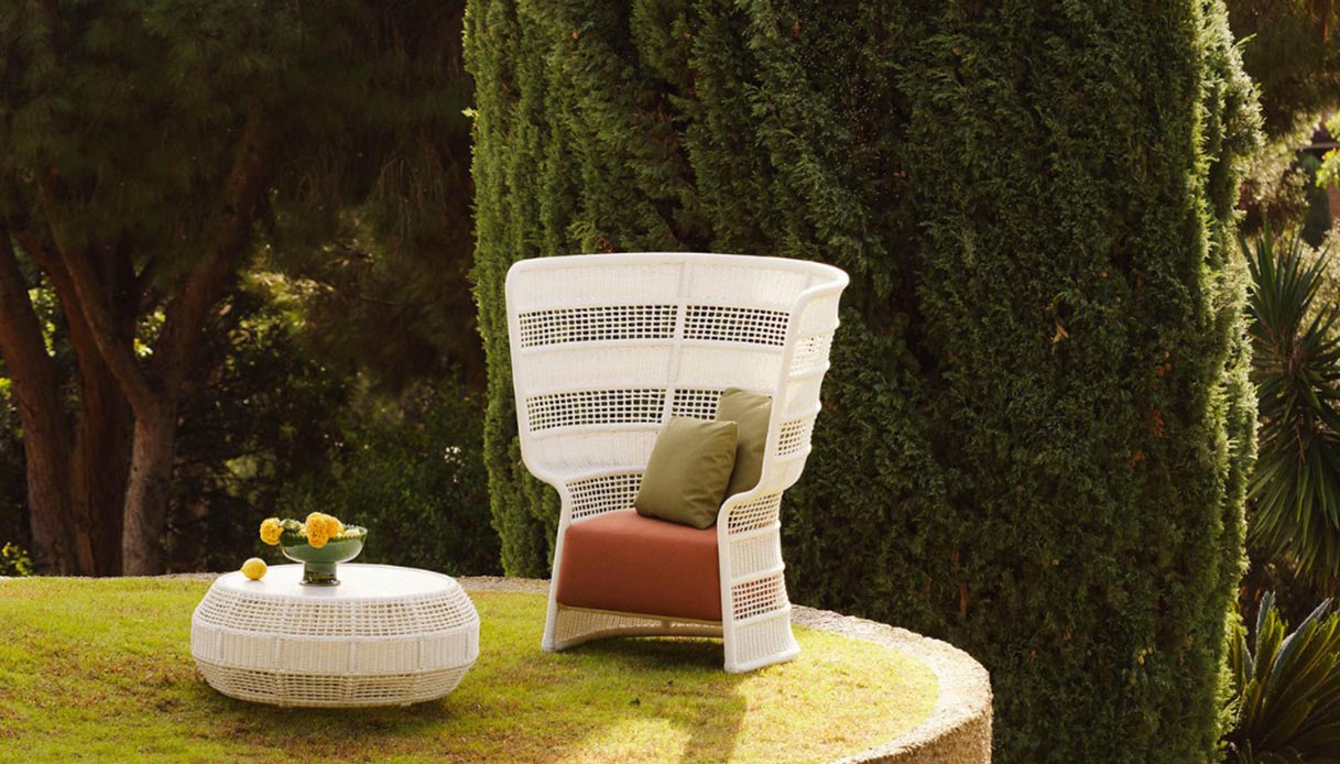 Poltrona outdoor Escala di Fabio Novembre per Point in intreccio bianco con schienale alto, in giardino tra cipressi