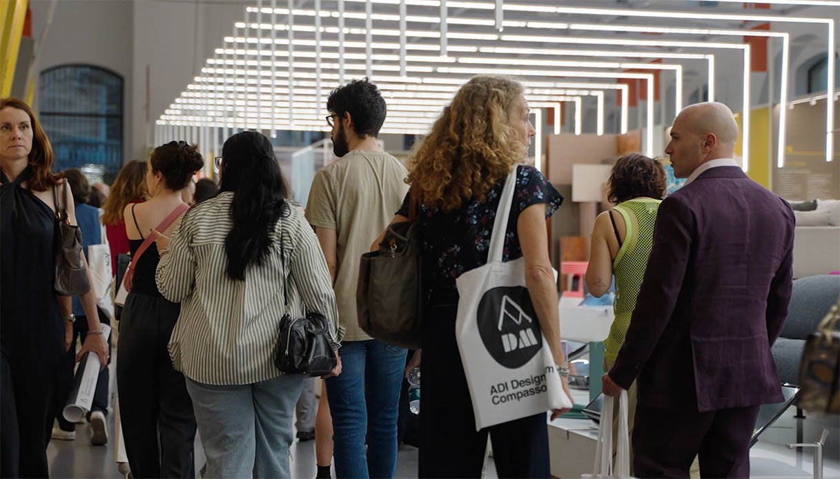 Visitatori all'interno dell'ADI Design Museum durante la mostra del Premio Compasso d'Oro, con installazioni luminose a soffitto