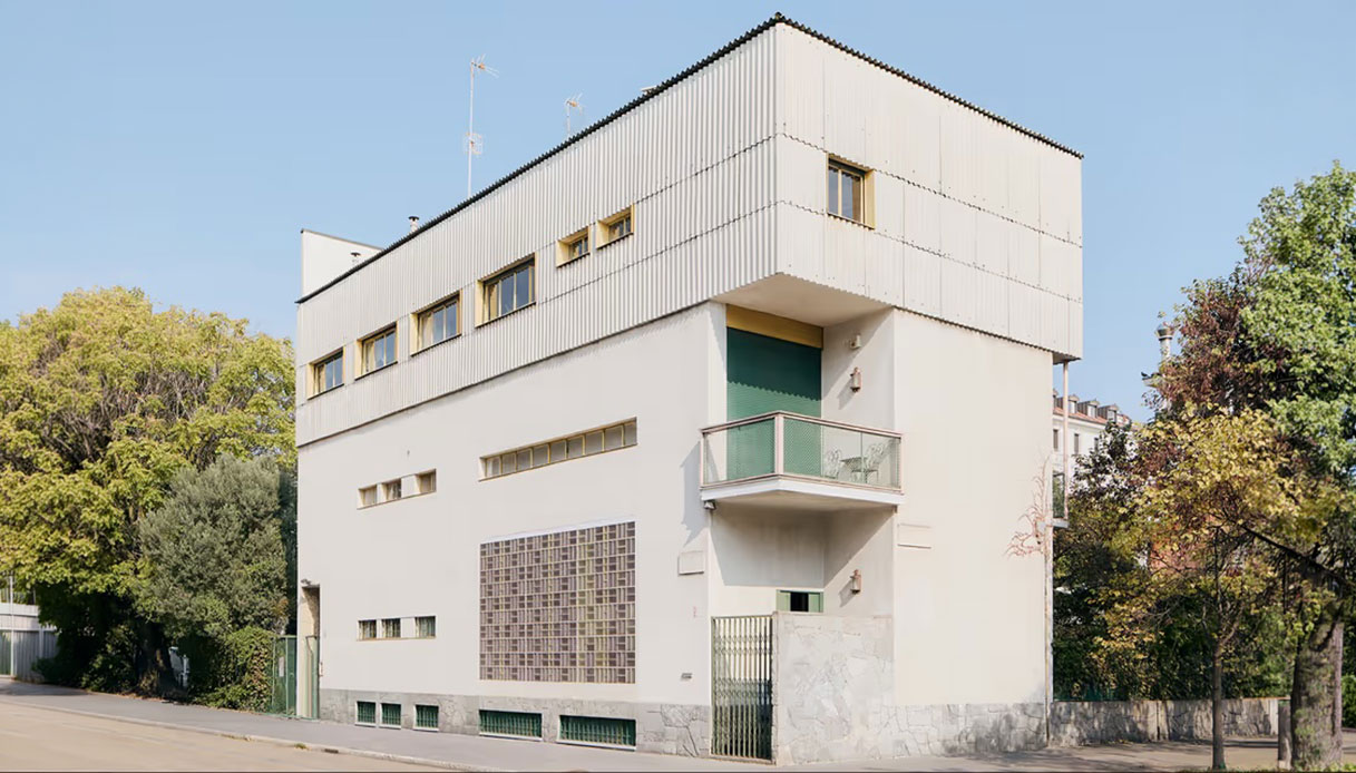 Facciata esterna di Villa Pestarini a Milano, edificio razionalista bianco con rivestimento metallico corrugato, vetrocemento e balcone verde, progettato da Franco Albini