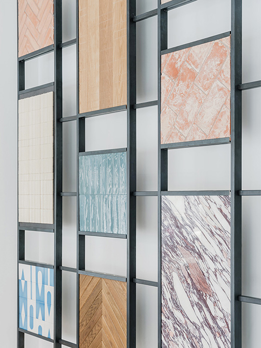 Dettaglio di pannello espositivo con campioni di parquet a spina di pesce, marmo rosa, ceramica effetto legno e lastre in toni blu e grigio