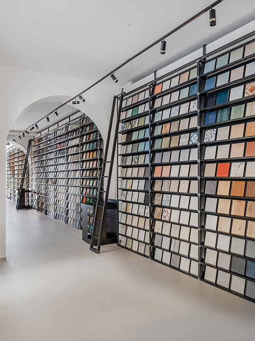 Libreria a parete con centinaia di campioni di materiali per interior design in struttura metallica nera, vista prospettica con arco bianco