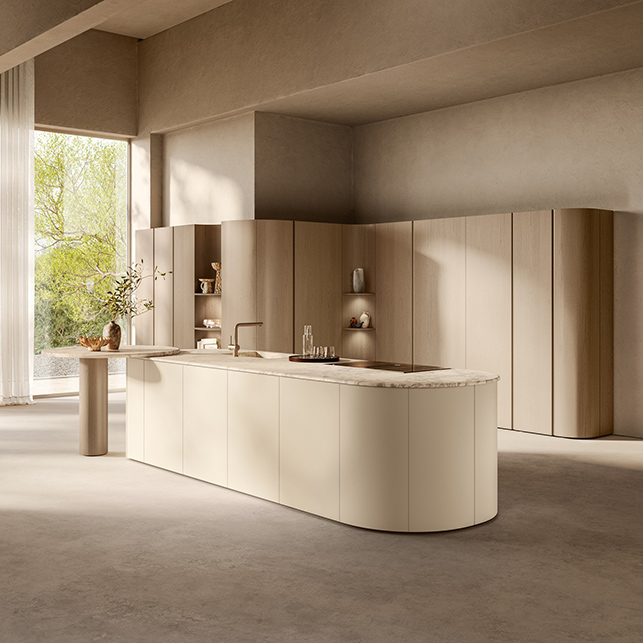 Cucina Scavolini Flair con grande isola ovale rivestita in laccato greige con rigature verticali, top in marmo bianco venato e colonne attrezzate in rovere sullo sfondo