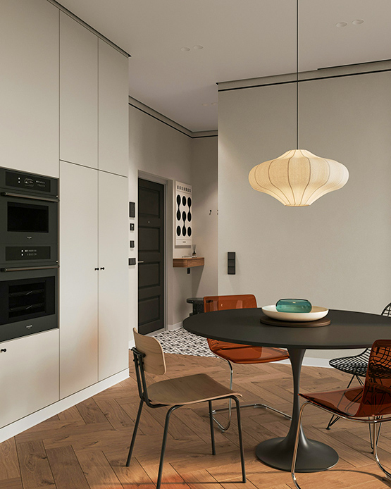 Cucina minimal con tavolo rotondo nero su base a tulip, sedie in diversi materiali, lampada sospesa in fibra naturale e pavimento a parquet spina di pesce