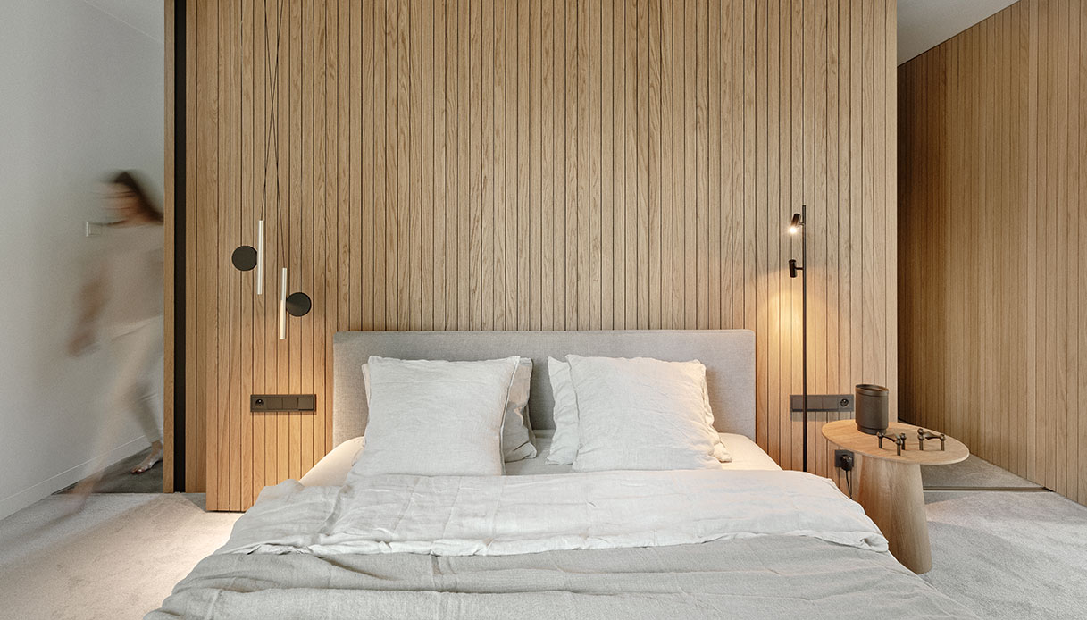 Camera da letto con parete in doghe di legno verticale e letto basso.