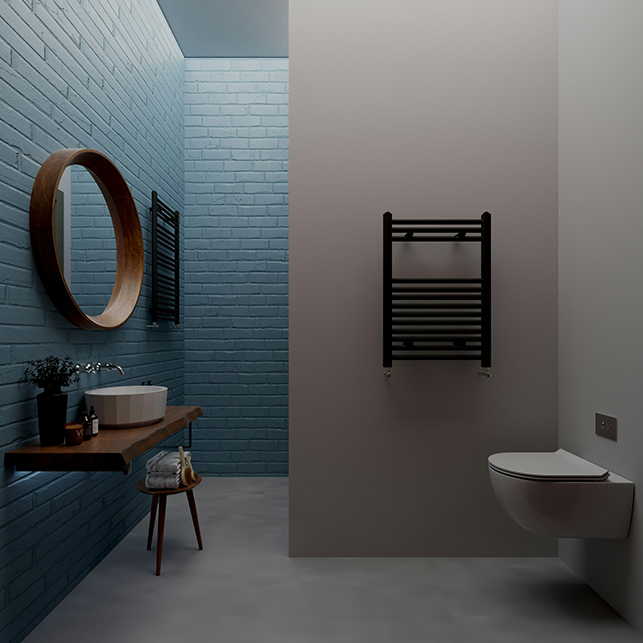 Bagno con parete rivestita in piastrelle rettangolari blu petrolio in posa sfalsata, lavabo rotondo in ceramica bianca su mensola in legno scuro, specchio tondo con cornice in legno, scaldasalviette nero e sanitario sospeso