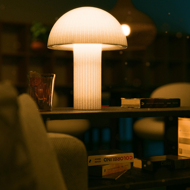 Lampada da tavolo a fungo in materiale traslucido bianco con coste verticali, illuminata in luce calda su ripiano con libri