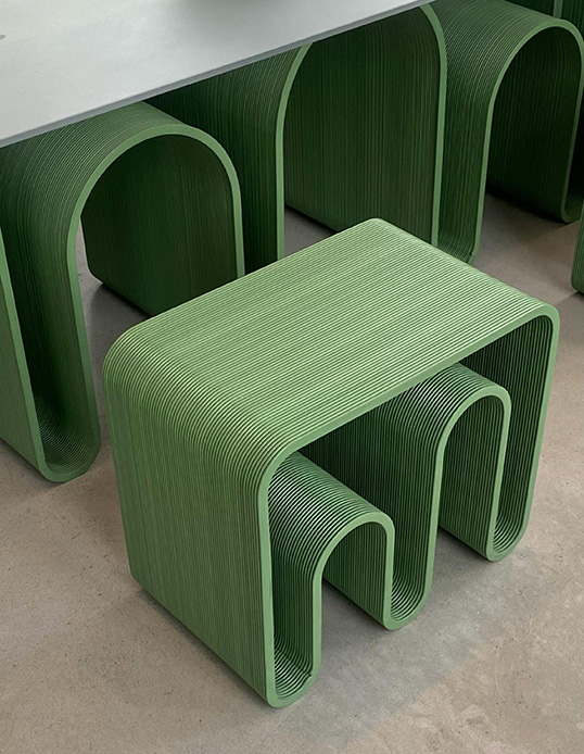Sedie e tavolino stampati in 3D con forma ad archi ripetuti in plastica verde salvia, texture a strati orizzontali