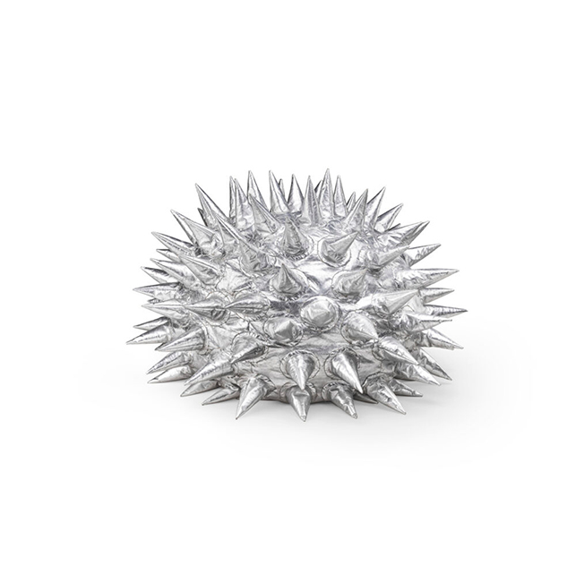 Pouf Fachiro di Marzio Cecchi per Gufram in eco-pelle effetto argento metallico, forma bassa e compatta interamente ricoperta da punte tridimensionali, su fondo bianco