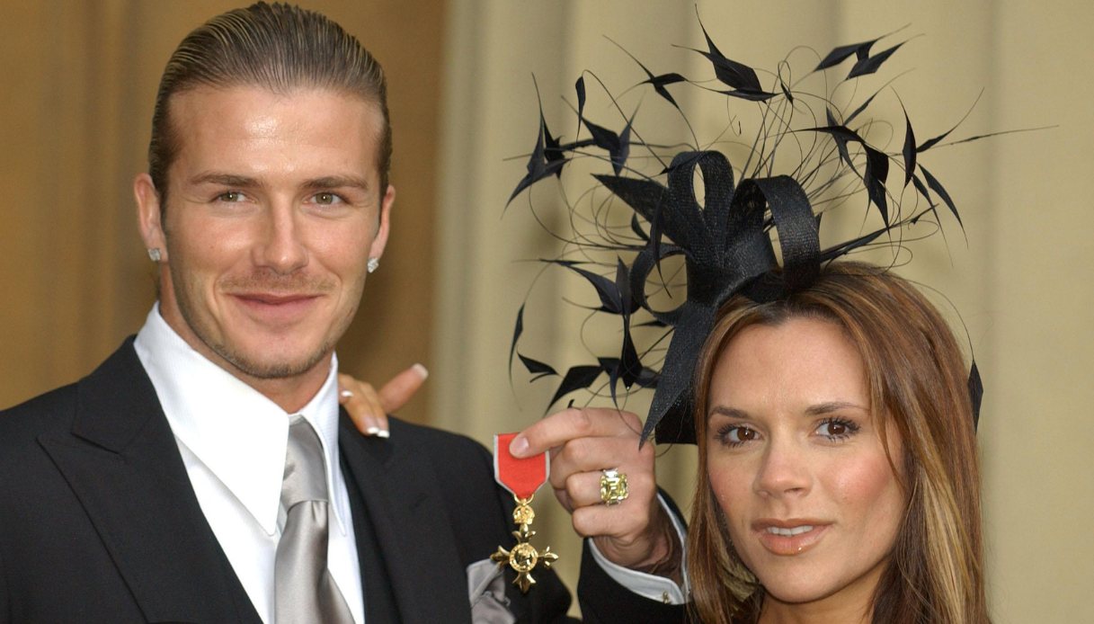 David Beckham insieme alla moglie Victoria, mentre tiene in mano l'OBE
