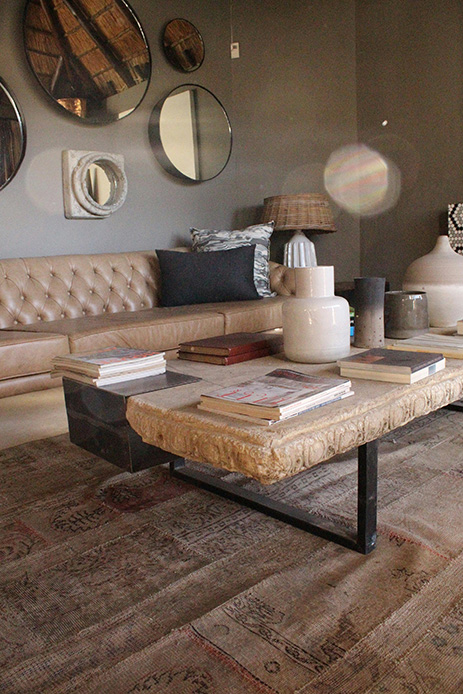 Ampio coffee table in pietra con libri impilati, riviste e vasi scultorei in soggiorno industrial