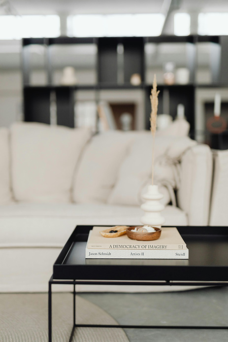 Coffee table nero con coffee table book impilati, ciotole in legno e vaso bianco in stile minimal