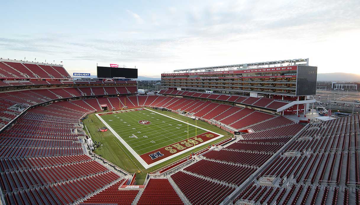 Panoramica interna del Levi's Stadium con le tribune rosse, la Suite Tower sul lato lungo e il campo da gioco al centro