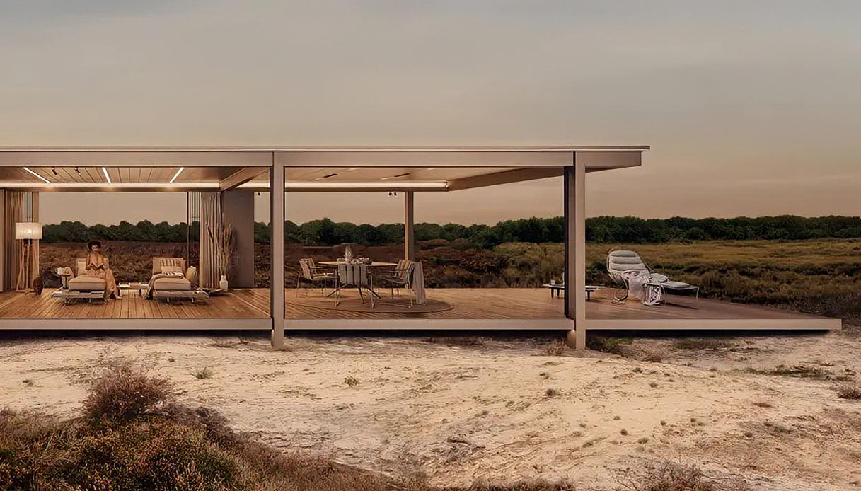 Pergola bioclimatica Renson Amani in alluminio grigio con struttura orizzontale aperta, arredata con divano e chaise longue, su piattaforma in legno immersa in un paesaggio naturale al tramonto