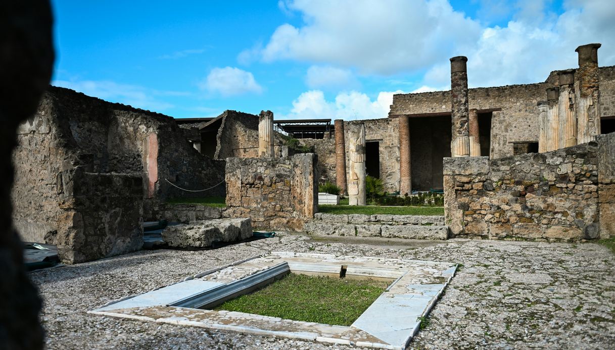 Atrio di una domus negli scavi di Pompei, con impluvium centrale, colonne e cielo azzurro