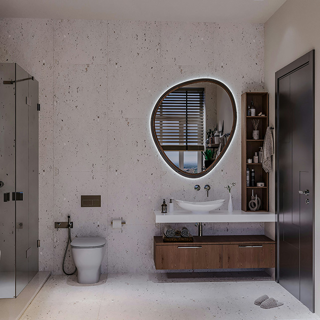Specchio dalla forma organica e asimmetrica, retroilluminato, sopra un lavabo con mobile in legno e colonna portaoggetti