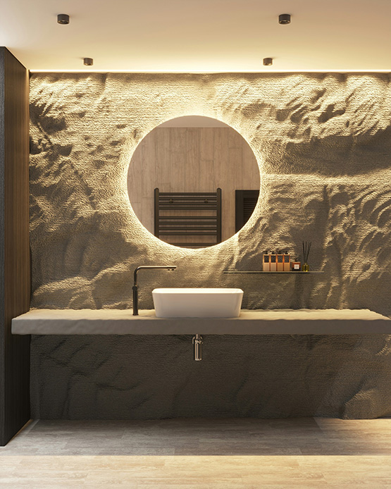Specchio rotondo retroilluminato su parete in pietra scolpita, con lavabo bianco e rubinetteria nera opaca