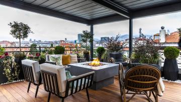 Sedute basse, tavoli curvi e piante in abbondanza. Il balcone raddoppia