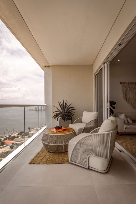 Terrazza con poltrone in corda intrecciata color tortora, tavolino basso con libro e binocolo, vista sul mare e sulla citt&agrave;