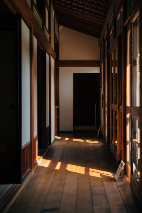 Corridoio di una casa tradizionale in legno, con pavimento a listoni scaldato dalla luce calda del sole