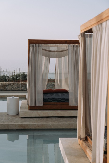 Daybed a baldacchino con tende in lino sospeso su una piscina