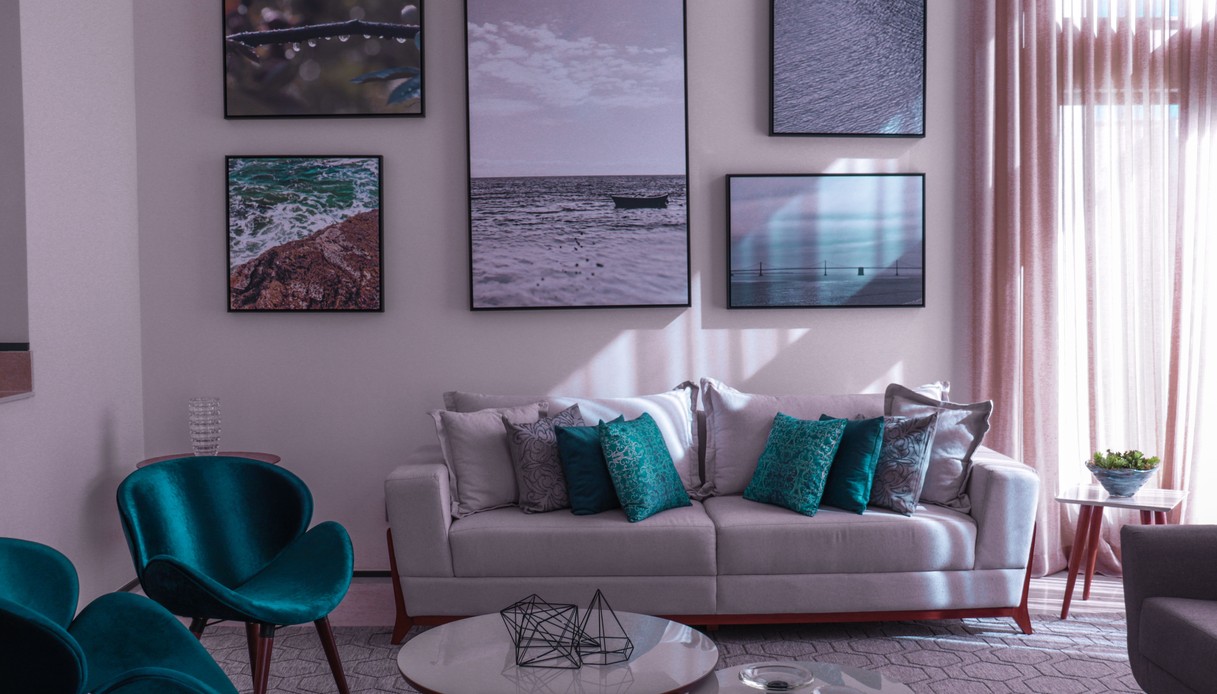 Gallery wall di cinque fotografie di mare e acqua in cornici nere sottili identiche, appesa sopra un divano chiaro
