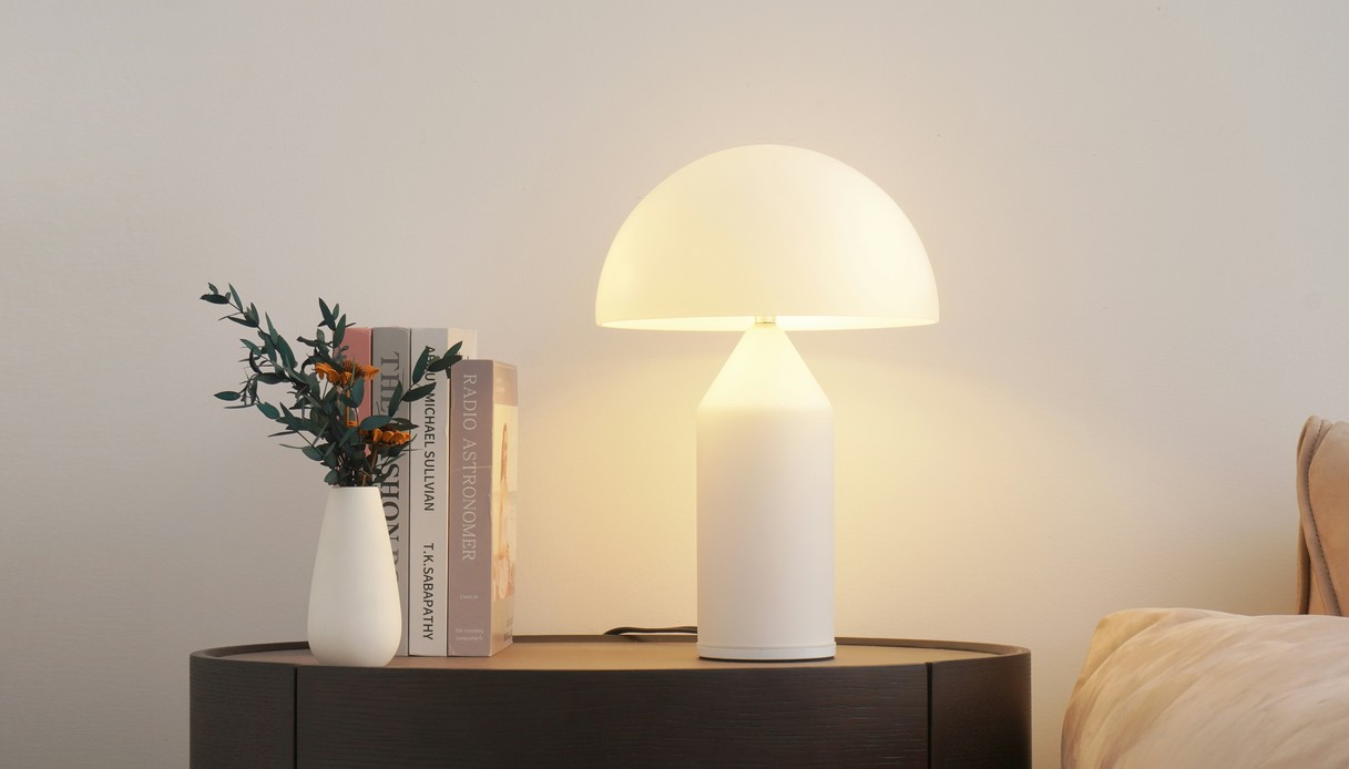 Lampada a fungo accesa su un comodino accanto a libri e fiori