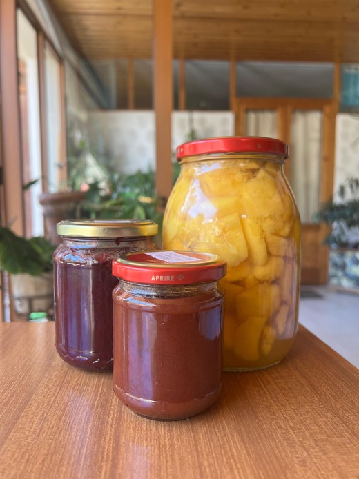 Vasetti di marmellata e un barattolo di frutta sciroppata su un tavolo