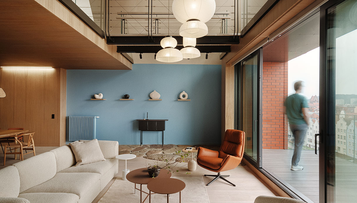 Living con parete azzurra, mensole con ceramiche e vetrata scorrevole aperta sulla terrazza