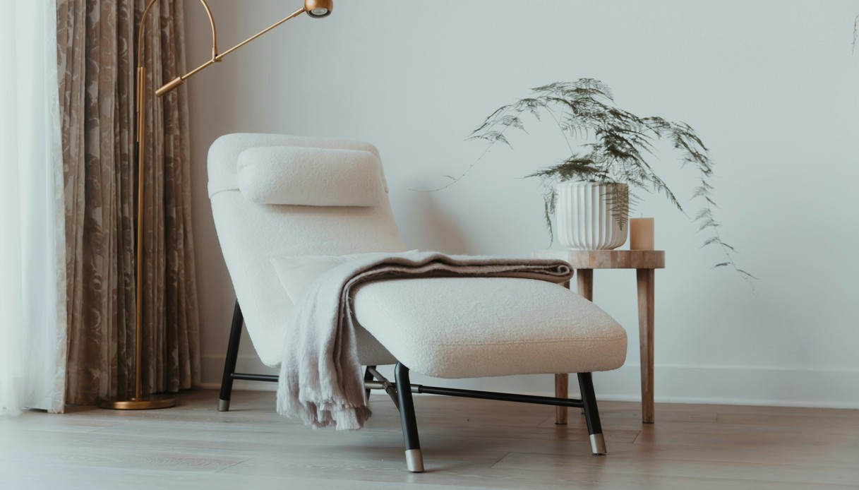 Chaise longue contemporanea in boucl&eacute; bianco con struttura nera e lampada da terra in ottone orientabile