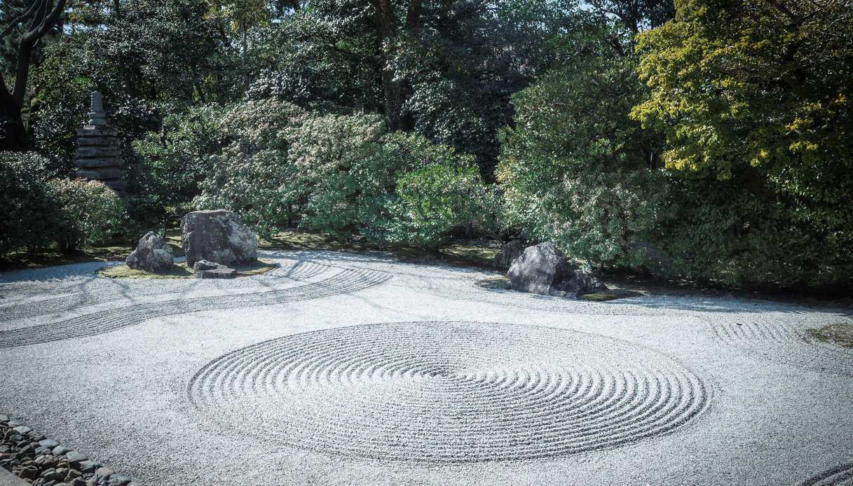 Giardino Zen con ghiaia bianca rastrellata a cerchi concentrici, rocce su isole di muschio e pagoda in pietra