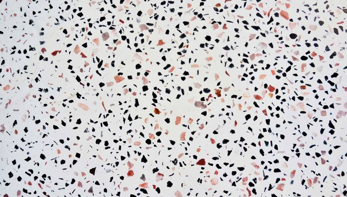 Pavimento in terrazzo alla veneziana con graniglia di marmo nera, rosa e rossa su fondo chiaro