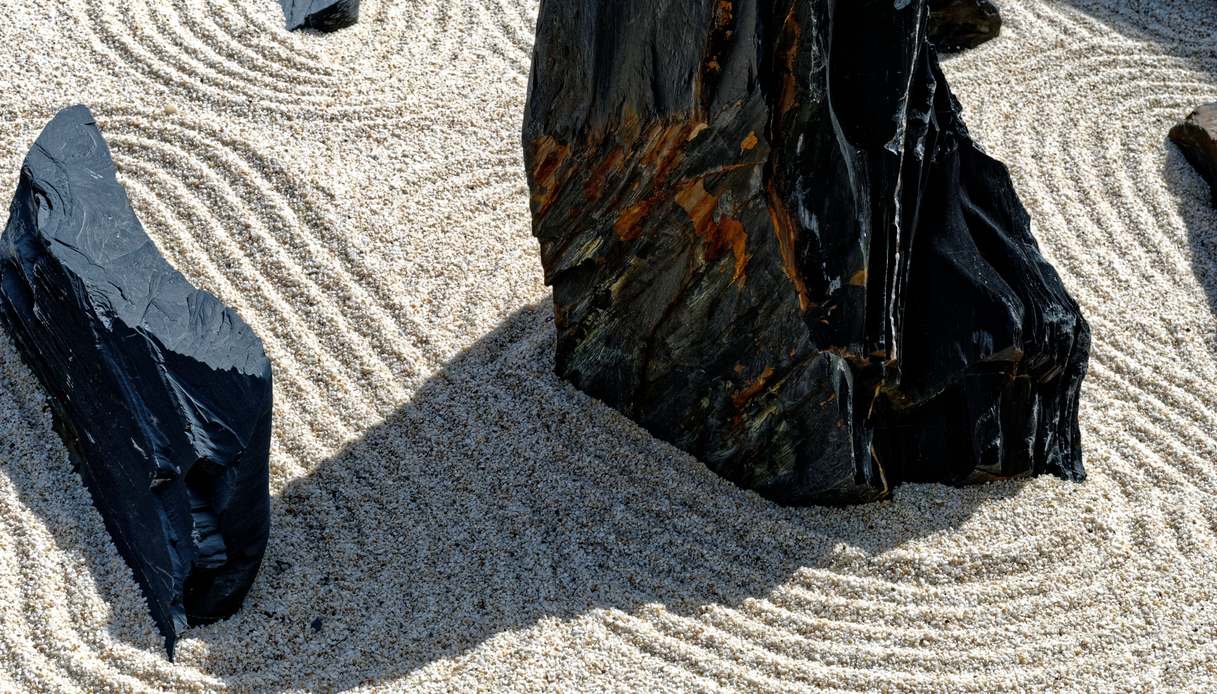 Dettaglio di rocce scure appoggiate su ghiaia bianca finemente rastrellata