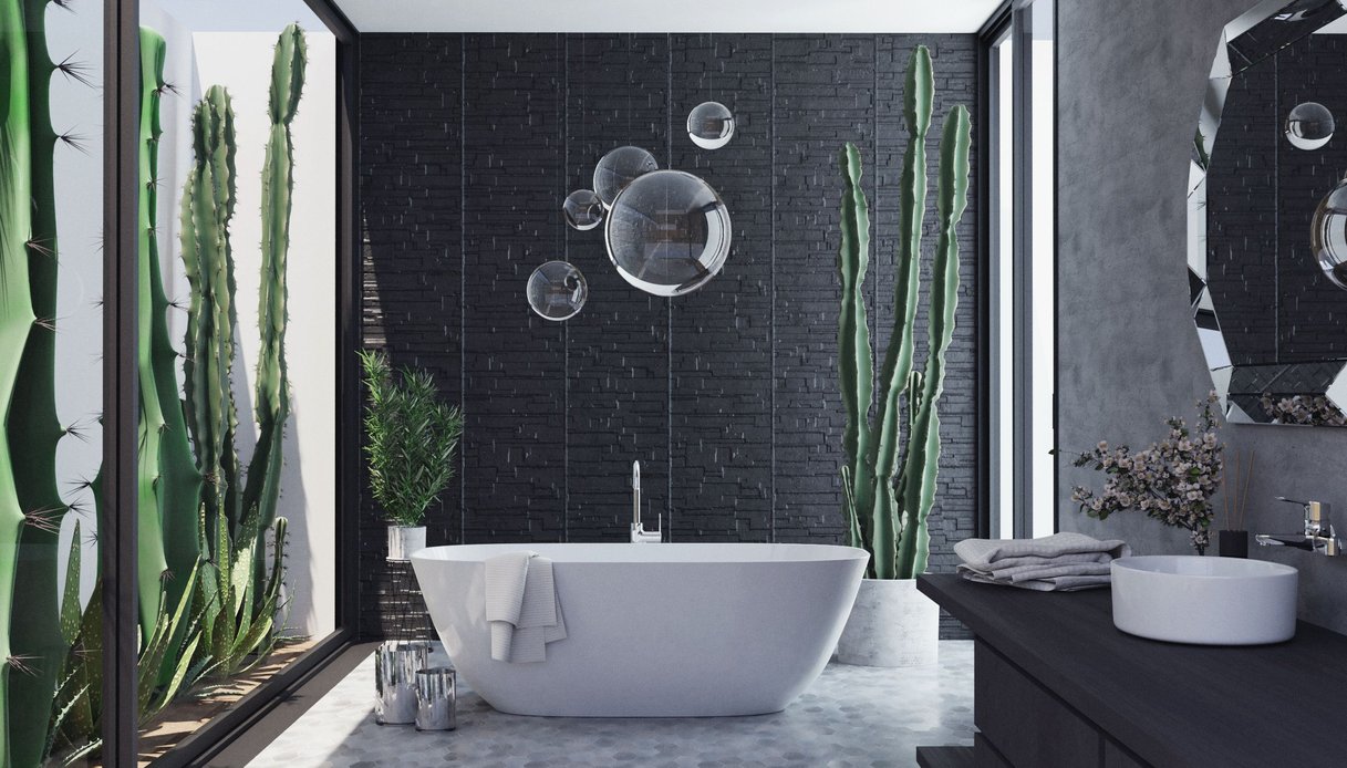 Bagno con parete in pietra nera a listelli, vasca freestanding bianca, lampade a sfera in vetro sospese, grandi cactus in vaso e vetrate su un giardino di piante grasse