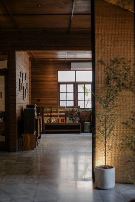 Stanza con pareti e soffitto rivestiti in doghe di legno scuro, espositore di vinili sotto la finestra e pavimento in marmo chiaro